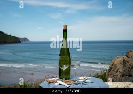 Tasting of txakoli or chacolí slightly sparkling very dry white wine produced in Spanish Basque Country, served outdoor with view on Bay of Biscay, At Stock Photo