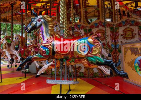 Fairground at Parsons Green, West London, UK; super-bright coloured rides, balloons, cars, trains and Spiderman Stock Photo