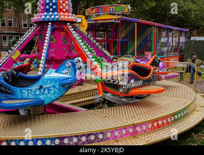 Fairground at Parsons Green, West London, UK; super-bright coloured rides, balloons, cars, trains and Spiderman Stock Photo