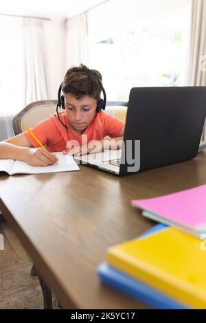 Caucasian boy learning and using laptop and headphones in living room Stock Photo