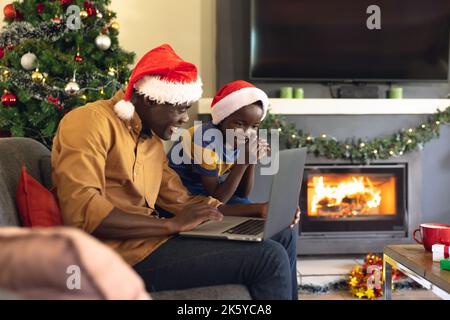 African american father and son siting on the sofa and using laptop Stock Photo