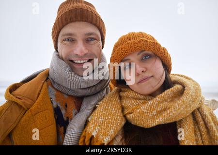 POV selfie photo of carefree young couple smiling at camera outdoors in winter, wearing warm clothes Stock Photo