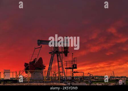 Oil drill rig and pump jack at sunset background. Oil production from ground. Drilling rigs at oilfield in desert. Natural resources, gas. Oil crisis, Stock Photo