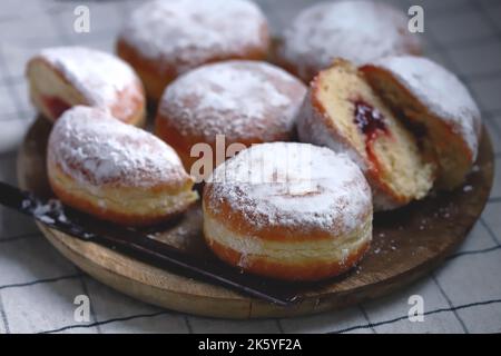 Berliner donuts in powdered sugar on a wooden tray. Stock Photo