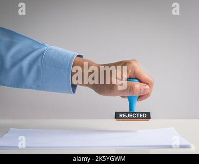 Rubber stamp, hand pressing on paper, with word Rejected. Stock Photo