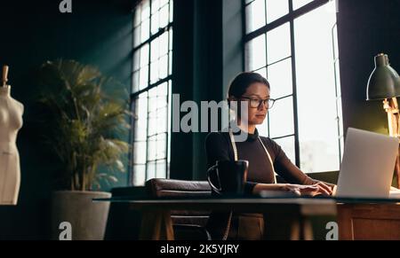 Young woman working at her workplace. Fashion designer using laptop at her office desk. Stock Photo