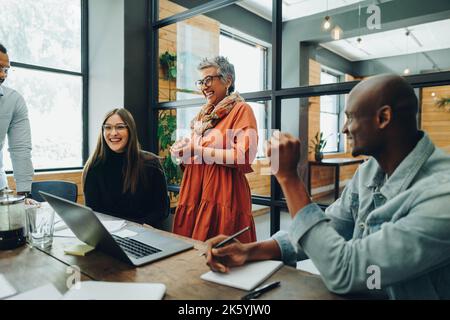 Diverse businesspeople smiling cheerfully during a meeting in a modern office. Group of successful businesspeople working as a team in a multicultural Stock Photo