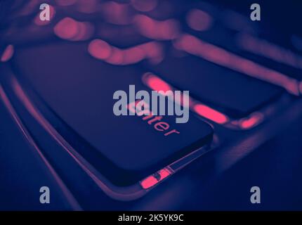 Closeup view of an enter key on a laptop keyboard with glowing lights and pink and blue color effect Stock Photo