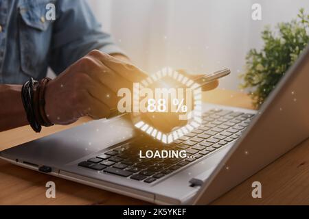 Casual Businessman Touching Mobile Phone or Smart Phone and Hexagonal Loading Module and Laptop Computer. Searching or Downloading Concept Stock Photo