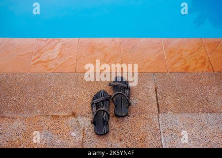 Holiday time. Sandal beside the swimming pool Stock Photo