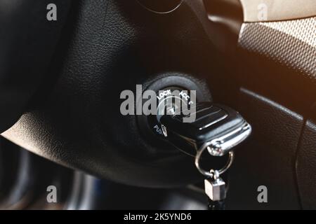 Key in car ignition lock under the steering wheel in a black interior Stock Photo