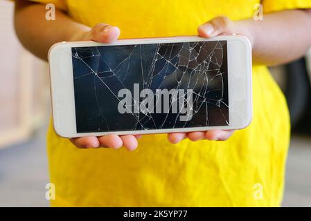 Kids holding a crack smartphone. Shallow DOF Stock Photo