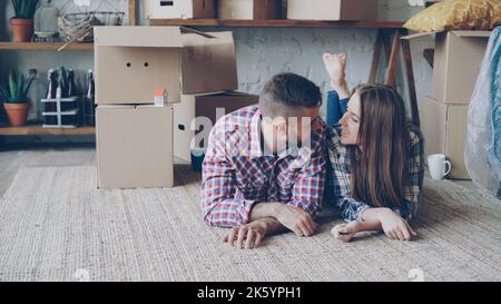 Happy couple is lying on floor in new house talking and smiling. Housing and relationship concept. Stock Photo