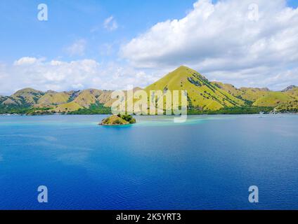 Aerial shot of beautiful blue lagoon at hot summer day with sailing boat. Komodo Island (Komodo National Park), Labuan Bajo, Flores, Indonesia Stock Photo