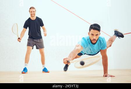 Two athletic squash players playing match during competitive court game. Fit active mixed race and caucasian athlete competing during training Stock Photo