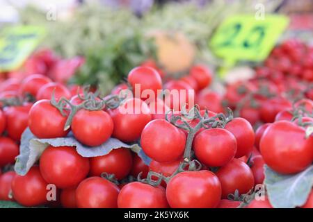 Red ripe cherry tomatoes on green branch at market Stock Photo