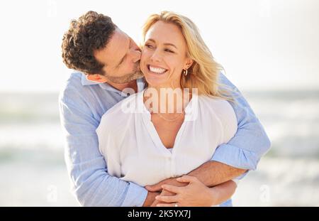 Closeup of an mature affectionate caucasian couple standing on the beach and smiling during sunset outdoors. Caucasian couple showing love and Stock Photo