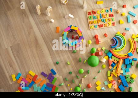 Alphabet wooden board with colored font letters. Colored wooden blocks for building and toy trees and plants. Top view. Stock Photo