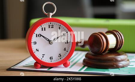 Judges hammer with red alarm clock on clipboard Stock Photo