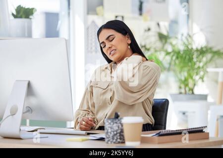 One mixed race businesswoman suffering from a neck pain while massaging herself and trying to release aching and tension at an office job. Young Stock Photo