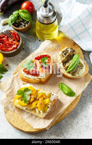 Open sandwiches set with salted salmon, sun dried tomato, grill aubergine, grill bulgarian pepper and cream cheese on a stone table. Healthy food, veg Stock Photo