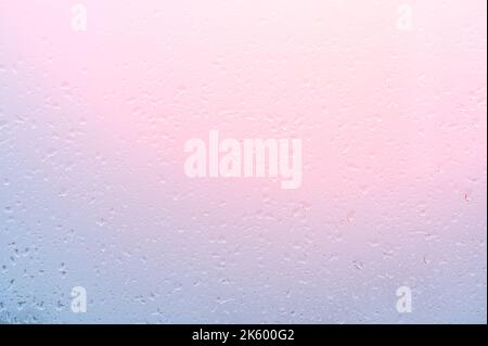 Water Drops Background. Rain drops on window on sunset, pink blue background. Drops Of Rain Water at dawn with pink Light On Glass Background. pink ba Stock Photo