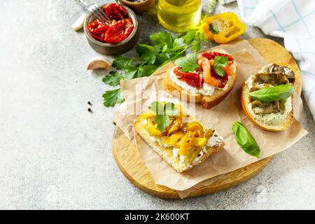 Open sandwiches set with salted salmon, sun dried tomato, grill aubergine, grill bulgarian pepper and cream cheese on a stone table. Healthy food, veg Stock Photo