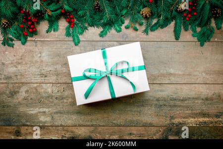 Christmas gift. Gift box and Christmas decorations. Christmas composition. Frame made of christmas gifts, pine branches on rustic wooden table. Flat l Stock Photo