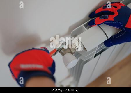 Man plumber installing heating radiator in apartment or house Stock Photo