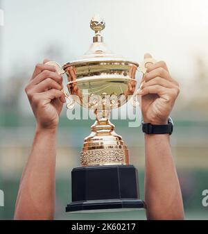 Closeup of unknown indian tennis player holding trophy and celebrating success after winning court game. Ethnic fit athlete holding prize award in Stock Photo