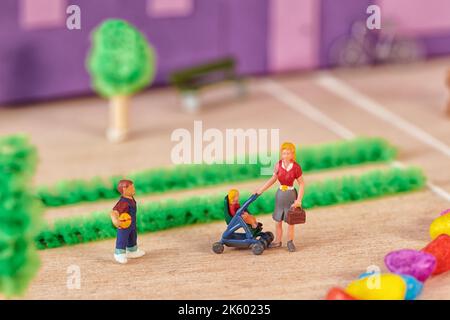 High angle of toy mom holding stroller with toddler near preschool son while walking together against home Stock Photo