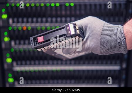 A hard disk for a raid in the hands of a man at a data storage server, close-up Stock Photo