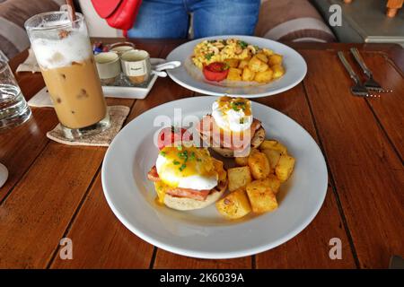 Close up scrambled and eggs benedict served with grilled potatoes and iced Cappuccino coffee Stock Photo
