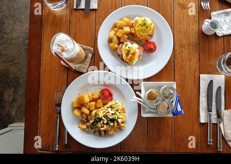 Close up scrambled and eggs benedict served with grilled potatoes and iced Cappuccino coffee Stock Photo