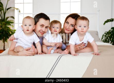 Portrait, large family, with triplets on the bed. Parents and small children. Medicine, eco Stock Photo