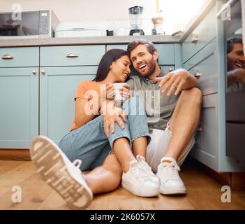 Young happy interracial couple bonding while drinking coffee together at home. Loving caucasian boyfriend and mixed race girlfriend sitting on the Stock Photo