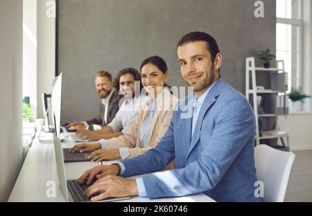 Group of happy smiling young business people working on laptop computers in office Stock Photo