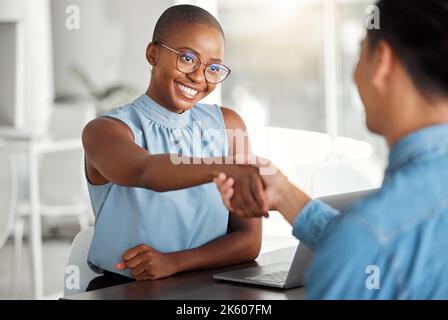 Two cheerful businesspeople shaking hands in a interview together at work. Happy colleagues greeting with a handshake in an office. African american Stock Photo