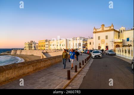 View across the bay and beach (Spiaggia della Purità) and waterfront facades of old town houses in evening sunlight in Gallipoli, Apulia, Italy. Stock Photo