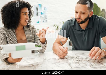 Two architectural coworkers planning a building project. Young designers working on a blueprint. Businesspeople collaborate on a building project Stock Photo