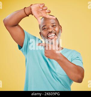 Portrait of a happy mature african man making a frame gesture with his hands against a yellow studio background. Life is full of happy moments and we Stock Photo