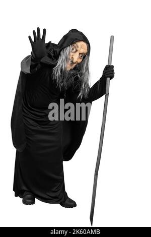 Old witch in a cloak standing with a stick isolated over white ...