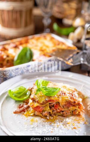 Lasagna with pesto.Italian lunch,homemade green lasagna with spinach in the dough, ragu - meat sauce, bechamel and parmesan cheese. illage dining atmosphere in Italy.  Stock Photo