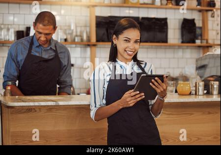 Portrait of a businesswoman ordering stock on her digital tablet. Business partners working together in restaurant kitchen. Entrepreneur using a Stock Photo