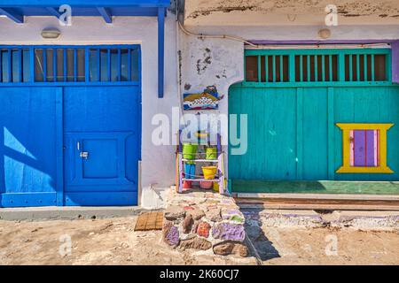 Colorful blue, green boat garage doors, Klima fishermen village, Greece. Painted and weathered wooden doorways, whitewashed walls.  Stock Photo