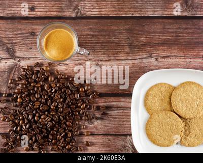 Heap of coffee beans, next to cup of coffee and plate with cookies Stock Photo