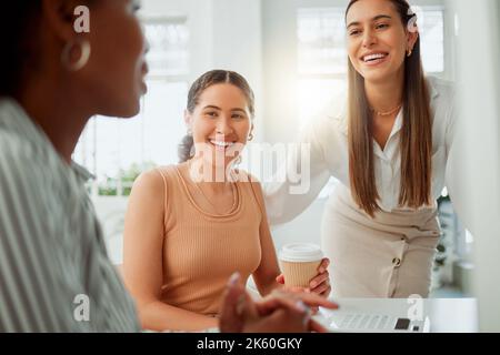 Group of confident smiling young business women brainstorming together in an office. Cheerful hispanic woman drinking coffee while listening to her Stock Photo