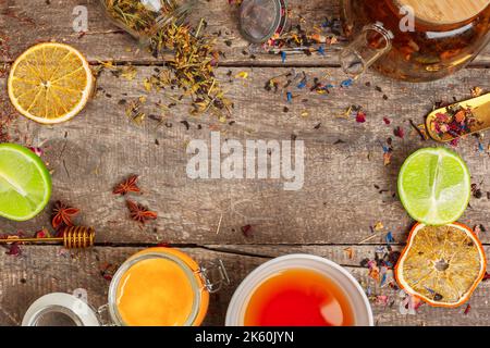 cups of healthy herbal tea with cinnamon, dried rose and camomile flowers in spoons over wooden background, top view Stock Photo