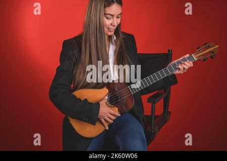 Beautiful young woman playing a CUATRO, typical Venezuelan instrument. Recording session, Concept of music and typical instruments. Stock Photo