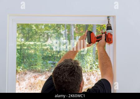 Professional technician is screwing the fastening to install blinds on windows of newly constructed house Stock Photo